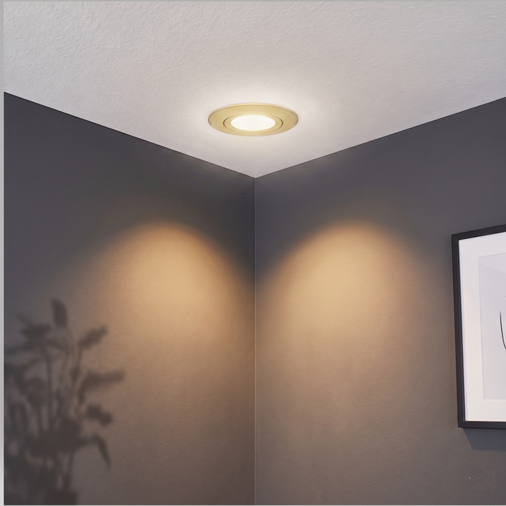 Gouden Miran inbouwspot gemonteerd in een wit gestuct plafond, sfeervol uitgelicht tegen een strakke antraciete wand.