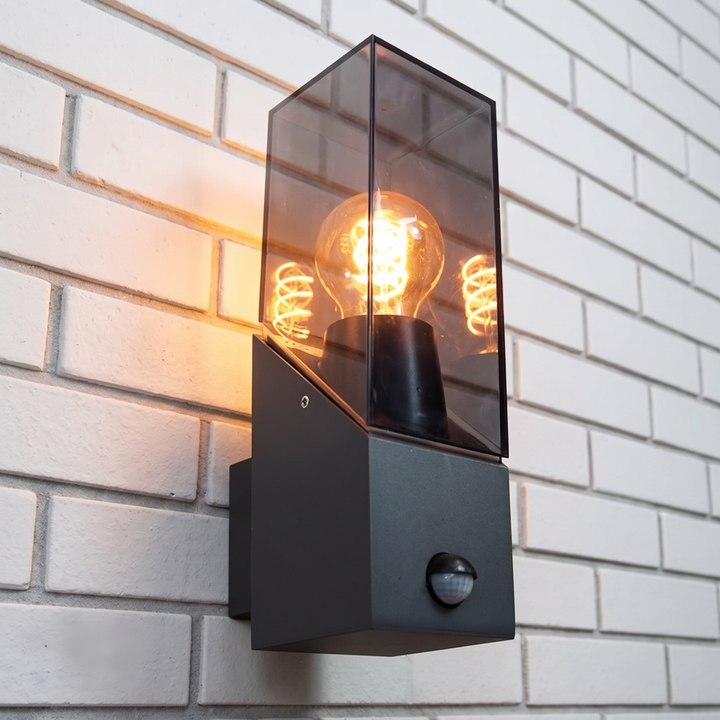 Gedetailieerde afbeelding van wandlamp Jasper met brandende sfeervolle ledlamp gemonteerd tegen een witte bakstenen muur