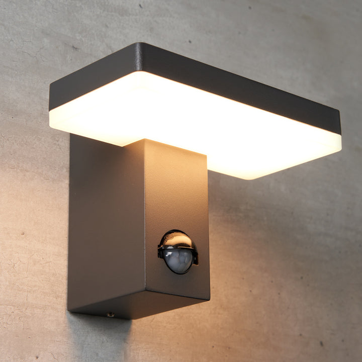 Matzwarte wandlamp met 2 senoren en tijdfunctie gemonteerd tegen een betonnen wand